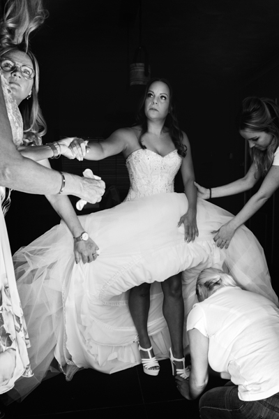 Bruid die hulp krijgt bij het aantrekken van haar trouwschoenen